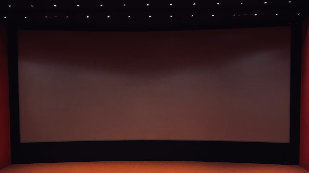 قاعة سينما بمقاعد حمراء وشاشة بيضاء فارغة.